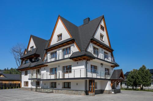 a large white building with a black roof at NOCLEGI ŁĘTOW-SKI in Białka Tatrzanska