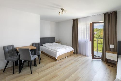 1 dormitorio con 1 cama, mesa y sillas en NOCLEGI ŁĘTOW-SKI en Białka Tatrzanska