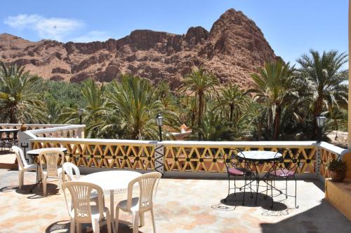 a patio with tables and chairs with a mountain in the background at Hotel AZUL Todra Gorges in Tinerhir