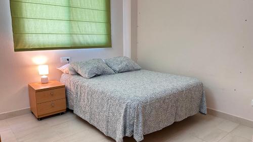 a small bedroom with a bed and a night stand at Apartamento Playa de Daimuz in Daimuz