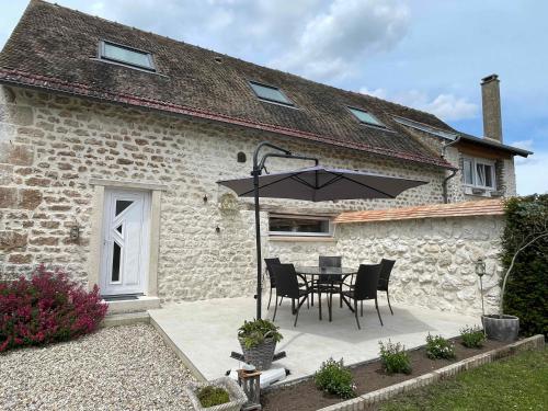 a patio with a table and chairs and an umbrella at L'histoire d'une hirondelle in Bouafles