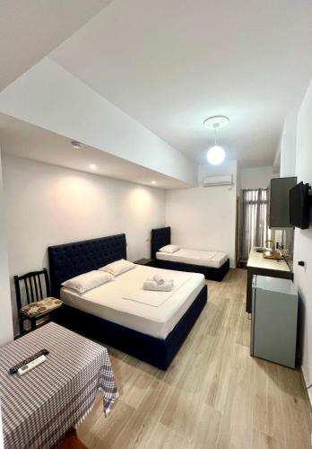 a hotel room with two beds and a tv at Hotel Villa Flowers 2 in Vlorë