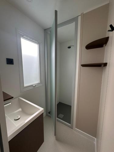 une salle de bain blanche avec un lavabo et une douche dans l'établissement Camping le Moulin de la Salle, à Les Sables-dʼOlonne
