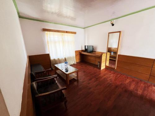 een lege woonkamer met een televisie en een tafel bij Hotel Lumbini in Leh
