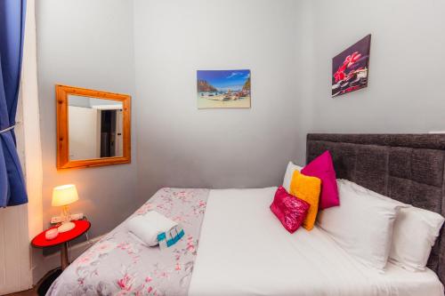 1 dormitorio con cama blanca y almohadas coloridas en Warm 1 Bed Apartment by Holyrood Palace and Park!, en Edimburgo