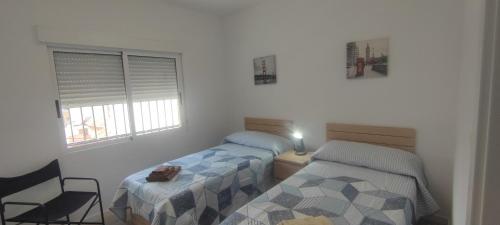 a bedroom with two beds and a chair and a window at Naquera House & Pool in Náquera