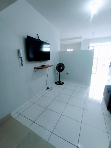 Dieses weiße Zimmer verfügt über einen TV und einen weißen Fliesenboden. in der Unterkunft Apartamento Mobiliado no Centro Comercial in Imperatriz