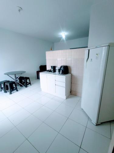 uma cozinha branca com um frigorífico e uma mesa em Apartamento Mobiliado no Centro Comercial em Imperatriz