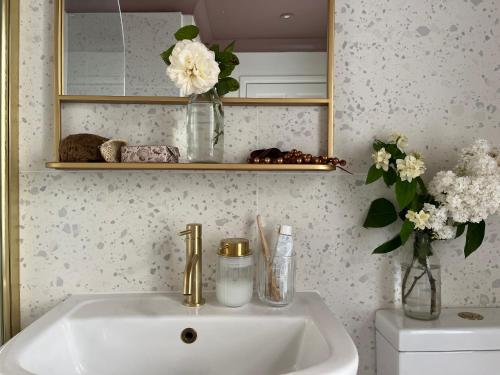 ein Waschbecken mit einem Spiegel und einer Vase aus Blumen in der Unterkunft Cute Georgian Cottage, central, newly renovated in Bath