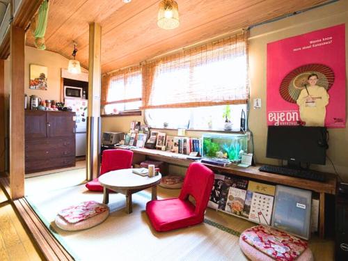 Habitación con sillas rojas, mesa y TV. en Guest House Pongyi, en Kanazawa