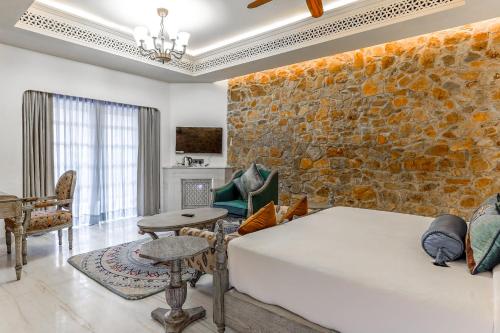 uma sala de estar com um sofá e uma parede de pedra em Juna Mahal Jungle Resort Ranthambore em Sawai Madhopur