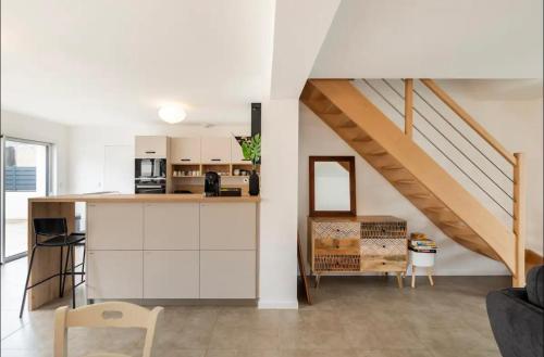 Una cocina con gabinetes blancos y una escalera. en La villa Hérault, en Cholet
