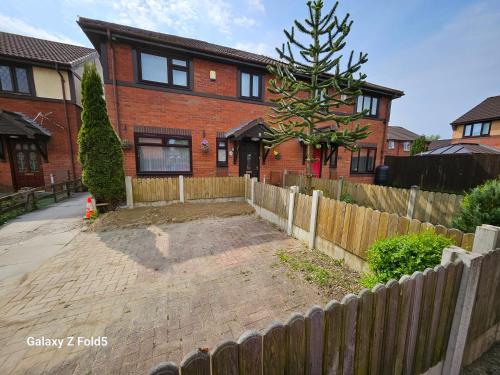a brick house with a fence in front of it at BRIGSTOCK HOLIDAYS HOUSE in Manchester