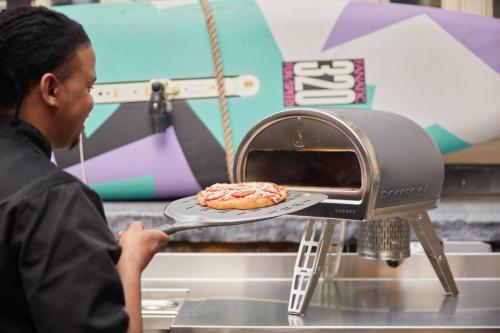 a man putting a pizza in an oven at The Montague On The Gardens in London