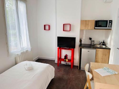 une chambre avec un lit et une cuisine avec un four micro-ondes dans l'établissement Lakanal 2 - Studio Prébendes Tours, à Tours