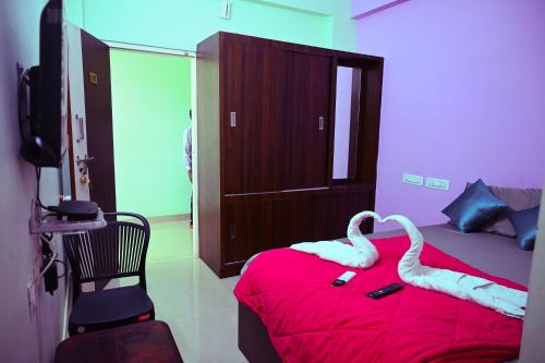 a bedroom with two swans on a red bed at Royal Rock INN in Harihar