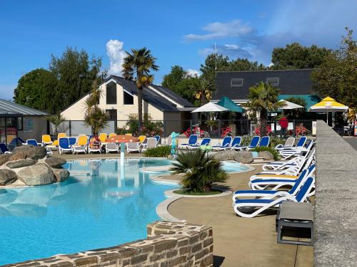a pool with blue and white chairs in a resort at Lebraz 2 in Saint-Lunaire