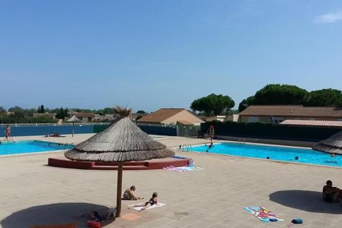 un groupe de personnes allongées autour d'une piscine avec un parasol dans l'établissement horizon bleu vendres plage Animaux bienvenues sur demande, à Vendres