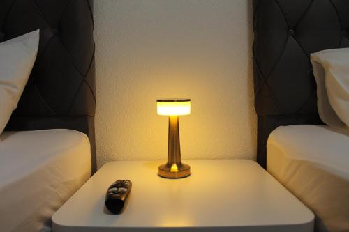 a lamp sitting on a table next to two beds at Sleep & Go Motel in Unterbalbach