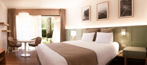 een hotelkamer met een groot bed en een tafel bij Résidence Hôtelière les Acanthes in Hossegor