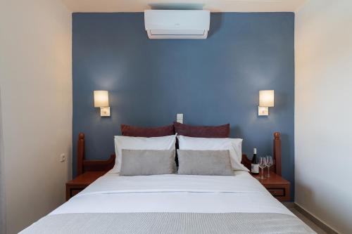 a bedroom with a blue wall and a white bed at Caldera Bay in Plataniás