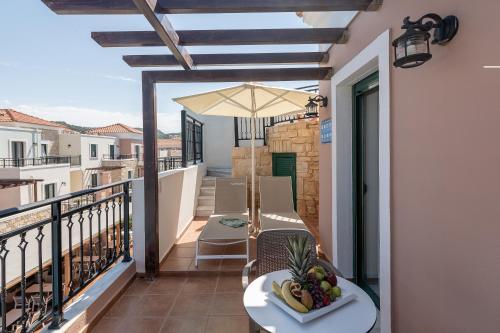 a balcony with a table and chairs and an umbrella at Caldera Bay in Plataniás
