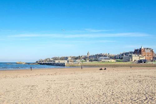 a beach with people sitting on the sand at Central St Andrews 2 bed apartment in St Andrews