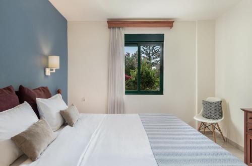 1 dormitorio con cama blanca y ventana en Caldera Bay en Plataniás