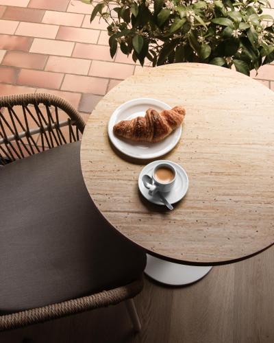 a table with a plate of food and a cup of coffee at Résidence Hôtelière les Acanthes in Hossegor