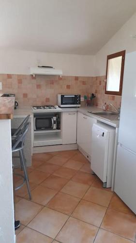 Il comprend une cuisine avec des appareils électroménagers blancs et du carrelage. dans l'établissement Bergerie en pierres et oliveraie, à Porto-Vecchio