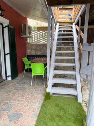 a staircase leading to a patio with a table and green chairs at Hamre Apartments (Nicholas) in Agios Georgios Pagon