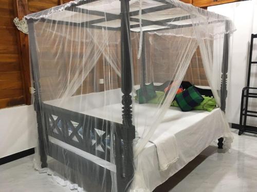 una cama negra con dosel y mosquiteros. en Gems Garden Guest House, en Tangalle