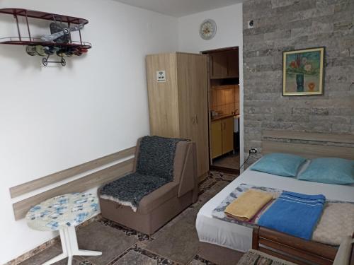 1 dormitorio con 1 cama y 1 silla en Mini Garsonjera en Podgorica