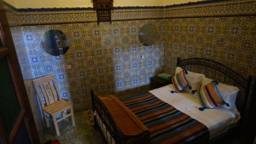a small bedroom with a bed and a chair at Dar Merzouga Meknes in Meknès