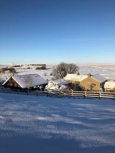 a house with snow covered roofs and a fence at Cosy Cottage near Brimham Rocks Yorkshire Dales in Grantley