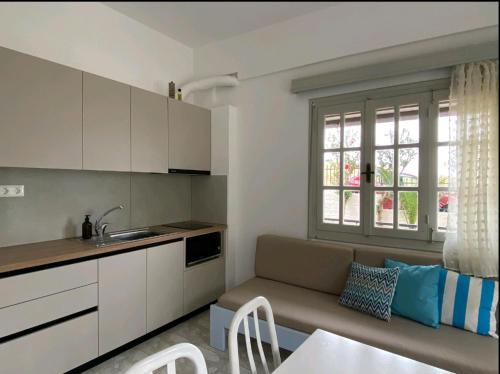 eine Küche und ein Wohnzimmer mit einem Sofa und einem Tisch in der Unterkunft Evita Bay Agia Pelagia Heraklion in Agia Pelagia