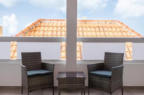 a patio with chairs and a table and a roof at Handelskade Penthouse in Willemstad