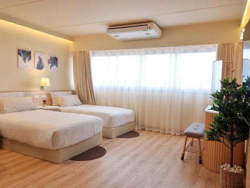 a hotel room with two beds and a window at ห้องพักเมืองทองธานี Happiness Sleep P1 in Ban Song Hong