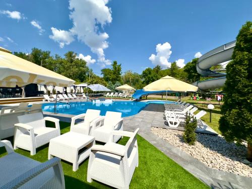 a pool with white chairs and a water slide at Club Hotel Pegasus in Tiszaug