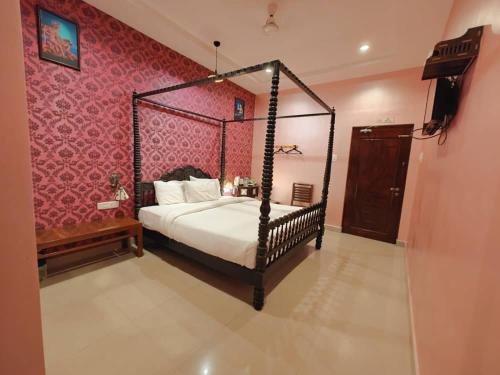 1 dormitorio con cama con dosel y pared de color rosa en Chola Heritage Resort en Kāraikkudi