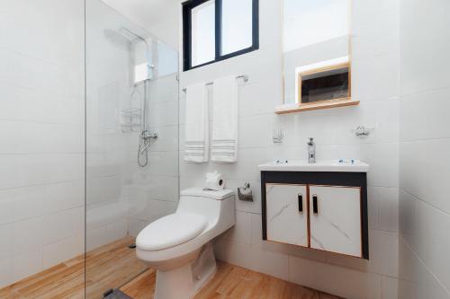 La salle de bains blanche est pourvue de toilettes et d'un lavabo. dans l'établissement Modern Luxury Apt w Outdoor Jacuzzi, à Santiago de los Caballeros