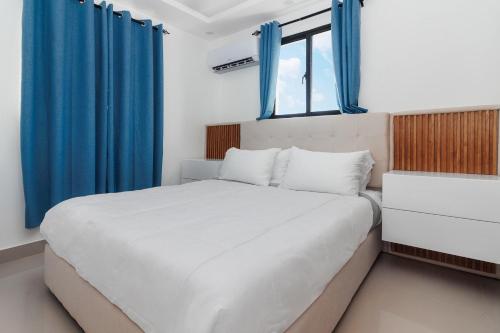 - une chambre avec un grand lit et des rideaux bleus dans l'établissement Modern Luxury Apt w Outdoor Jacuzzi, à Santiago de los Caballeros