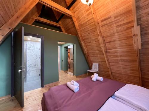a bedroom with a bed with two pink slippers at Qafqaz Suite Paradise Chalet & SPA in Gabala