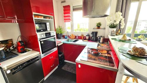 una cucina con armadi rossi e bancone con prodotti alimentari di Appartement avec balcon proche Paris & Disneyland a Champigny-sur-Marne