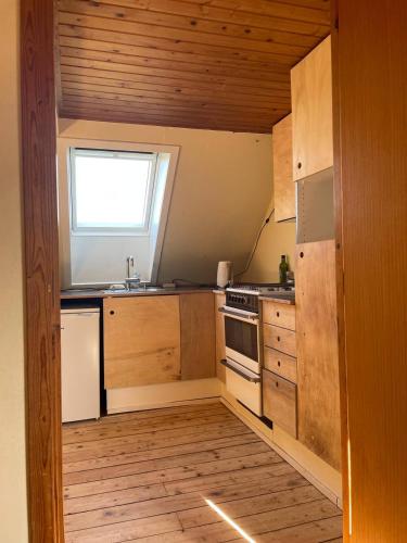 a kitchen with a stove and a sink and a window at Homestay in charming house on the countryside in Rønne