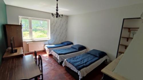 ミエルノにあるPokoje w Mielnie "Polikarp"のベッド2台、テーブル、窓が備わる客室です。