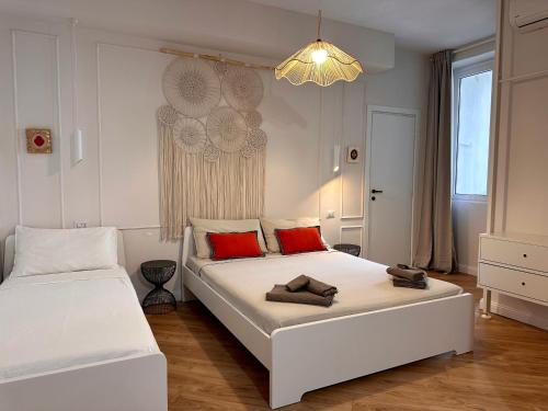 biała sypialnia z 2 łóżkami i żyrandolem w obiekcie Art’n’ shelter apartament w mieście Bari