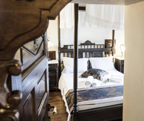 a bedroom with a four poster bed with a dog laying on it at Ινω Superior Suite 1856 Makrinitsa Pelion in Makrinitsa