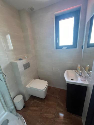 a white bathroom with a toilet and a sink at Sunset Beach in Sarbinowo