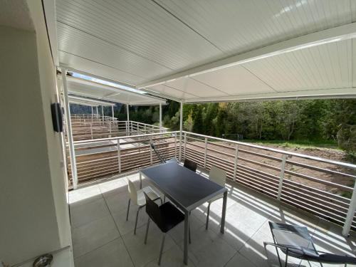 a room with a table and chairs on a balcony at Appartement chaleureux au pied des pistes in Orbey